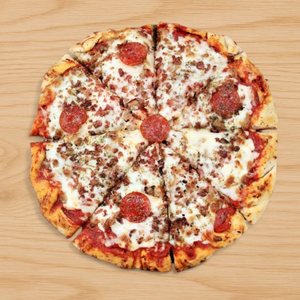 Babe's Pizza with pepperoni, sausage, and bacon, sliced into eight pieces on a wooden surface.